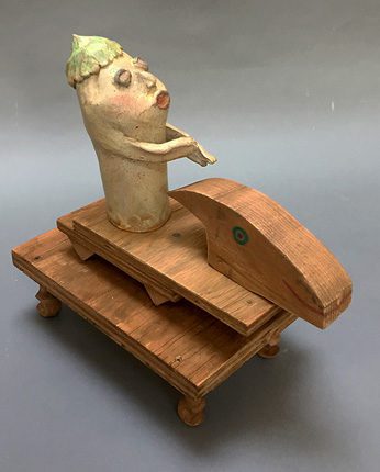 A wooden sculpture of a fish sitting on top of a wooden platform.