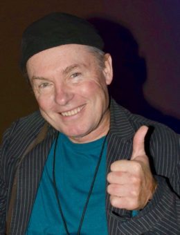 A man giving a thumbs up with a hat on.