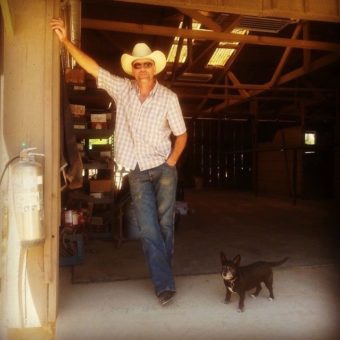 A man in a cowboy hat standing next to a dog.
