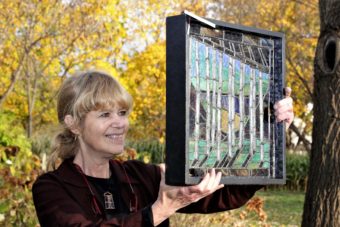 A woman holding up a stained glass window.