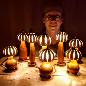 A woman is standing in front of a group of pumpkin lamps.