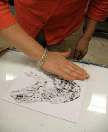 A woman drawing a frog on a piece of paper.