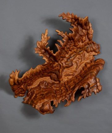 A wooden sculpture of a tree with leaves on it.
