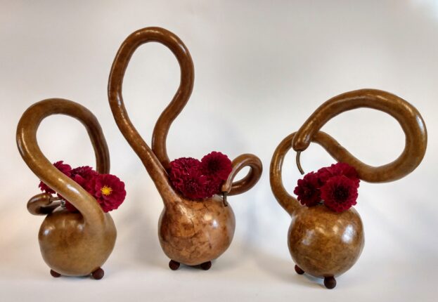 Three wooden vases with flowers in them.