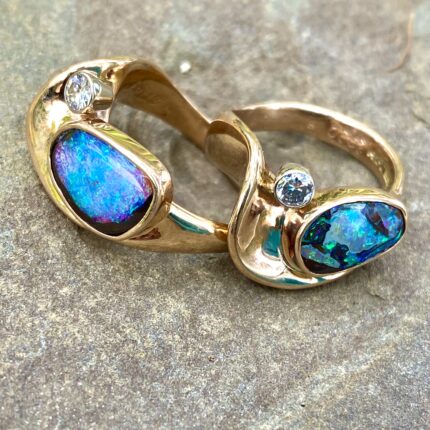 Two rings with opals and diamonds on a rock.