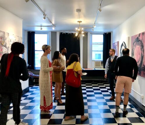 A group of people looking at paintings in an art gallery.
