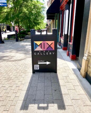 A sign for the mixx gallery on a sidewalk.