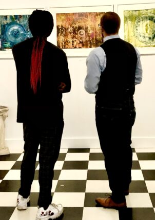 Two men looking at paintings in an art gallery.