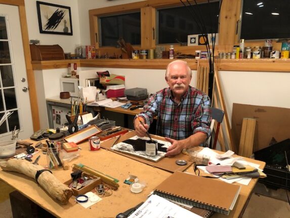 A man sitting at a table with a lot of tools.