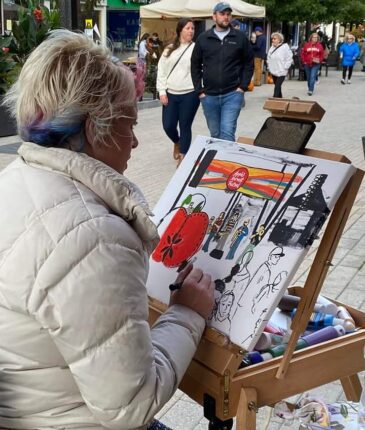 A woman is painting on an easel in a city.