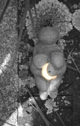 A black and white photo of a statue with a moon on it.