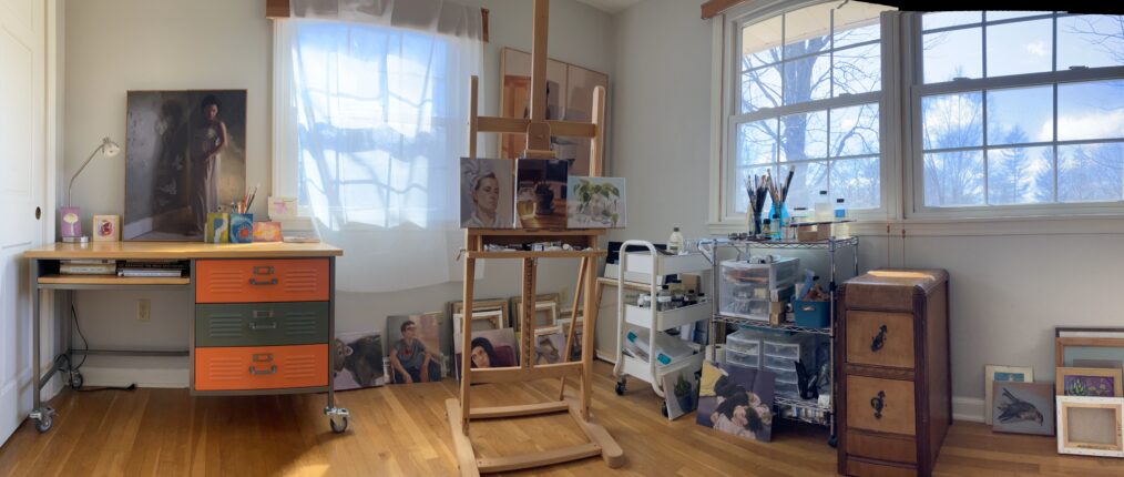 A room with an easel, paintings, and a window.