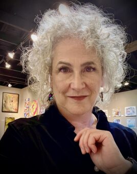 A woman with curly hair in an art gallery.