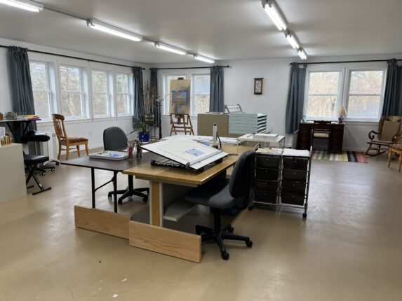 An empty art studio with a desk and chairs.