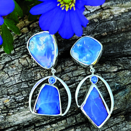 A pair of blue opal earrings on a piece of wood.