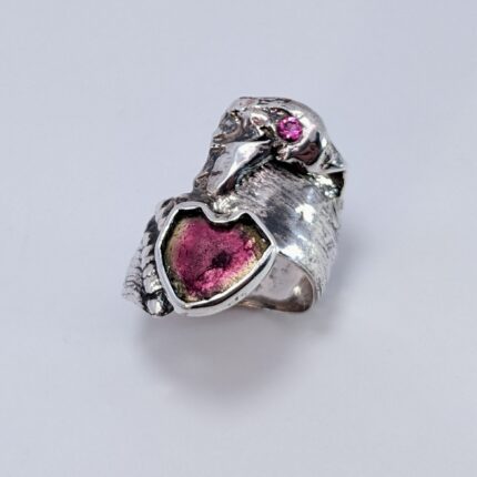 A ring with a bird and a pink stone.