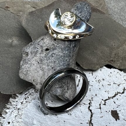 A gold and silver ring sitting on a rock.