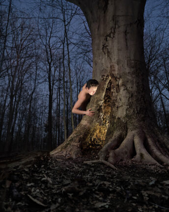 A man is standing in front of a tree