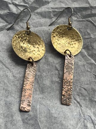 A pair of earrings with two different metal discs and one is made from copper.