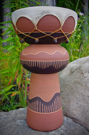 A large brown and black vase sitting on top of a rock.