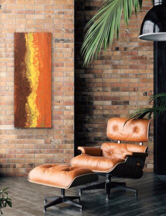 An orange abstract painting hangs above a leather chair in a living room.