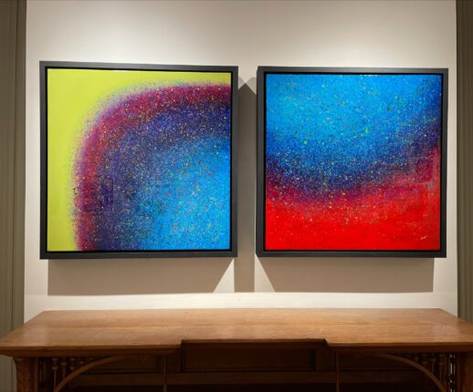 Two framed paintings on a table in an art gallery.