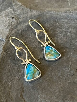 A pair of earrings with blue opal stones on top of a rock.