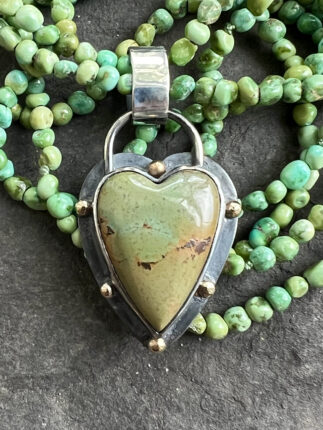 A heart shaped pendant with a green stone.