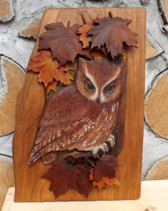 A wood carving of an owl with leaves on it.