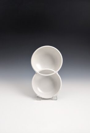 Two white bowls on a stand with a black background.