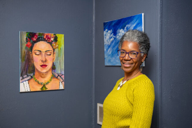 A woman standing in front of two paintings.