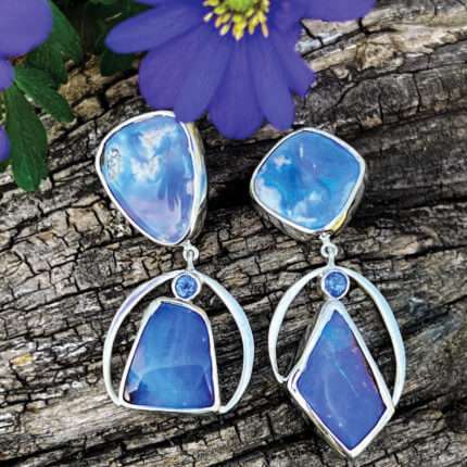 A pair of earrings with blue opals and purple flowers.